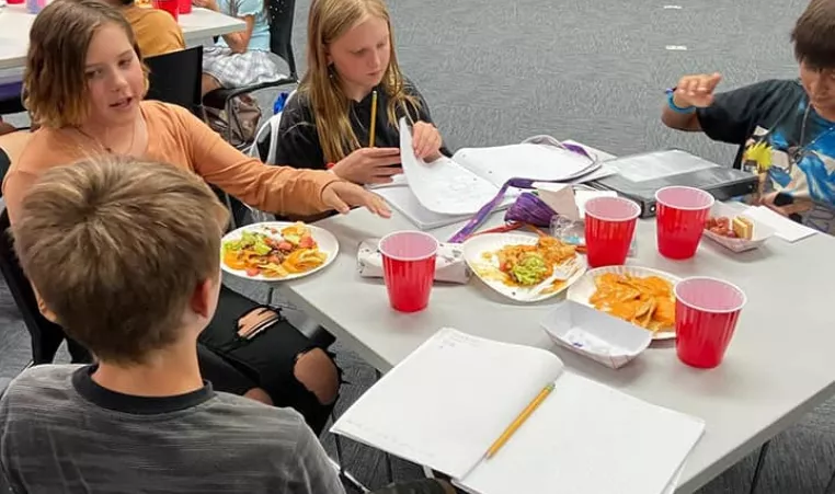 teens sitting at table eating homework 