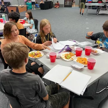 teens sitting at table eating homework 