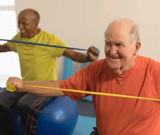 men on exercise ball stretch band